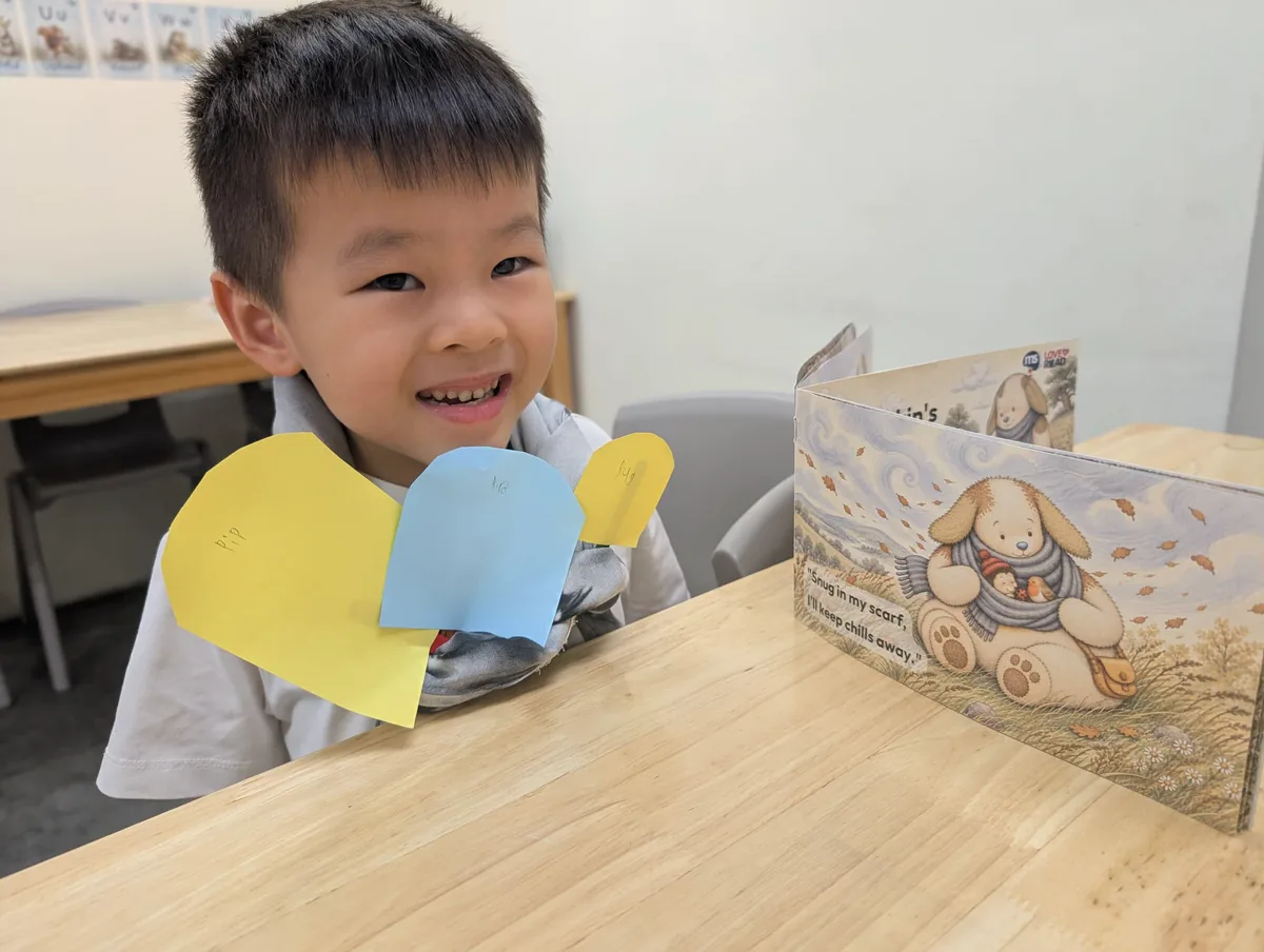 A smiling child holding up colourful paper leaves, beside a StoryQuest reader